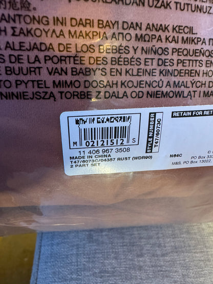 Close-up of the back of a plastic bag or package with printed text in multiple languages and a white barcode label. The product itself appears translucent smoky brown or gray plastic.