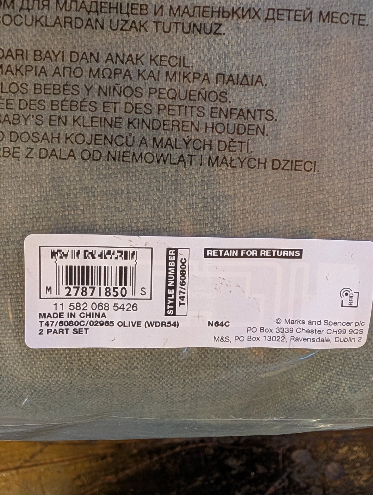 Close-up of the back of a woven fabric pouch with printed multilingual text and a white barcode label near the bottom.